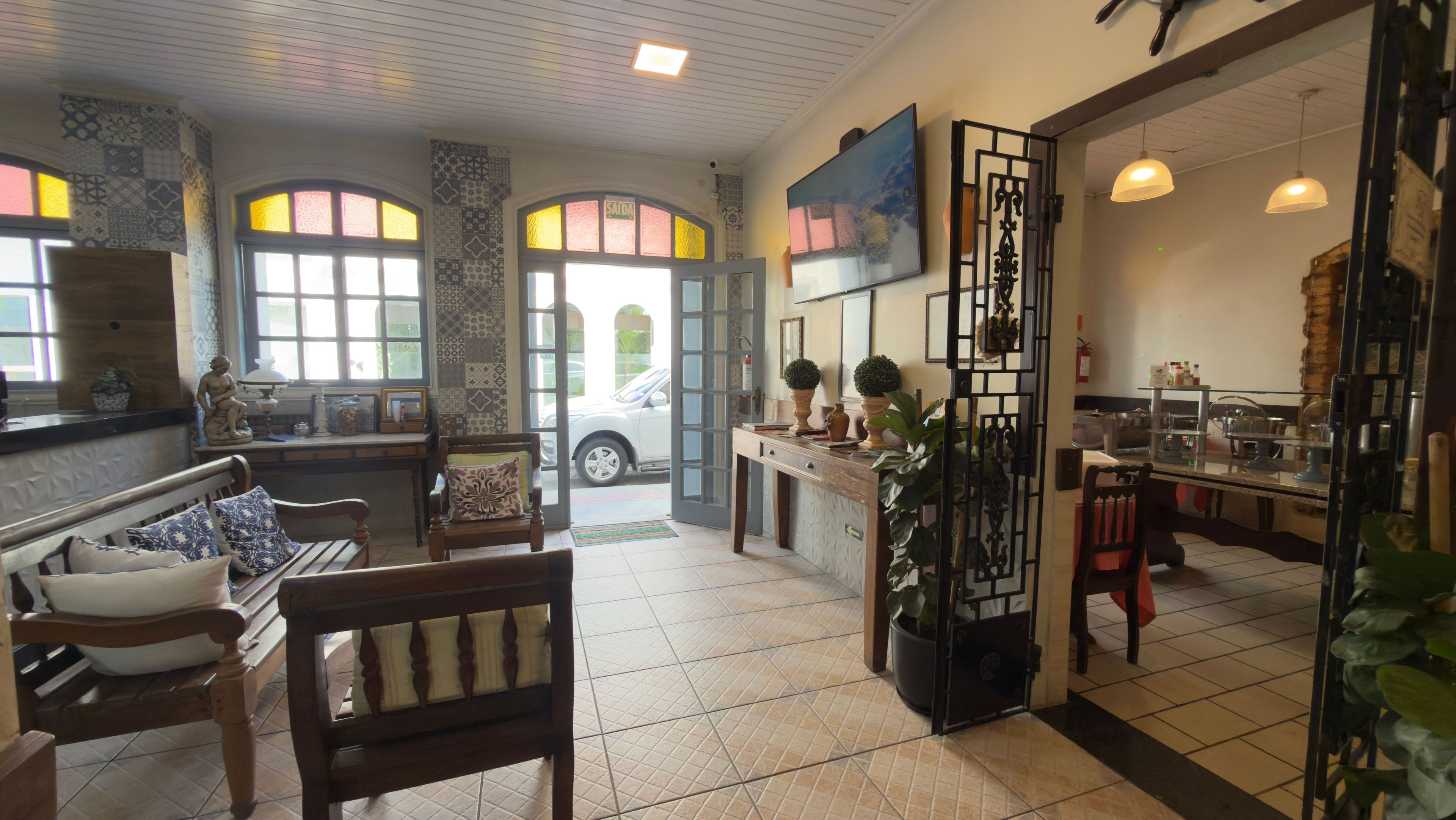 A hotel lobby with a reception desk, seating area, and a view of the street.