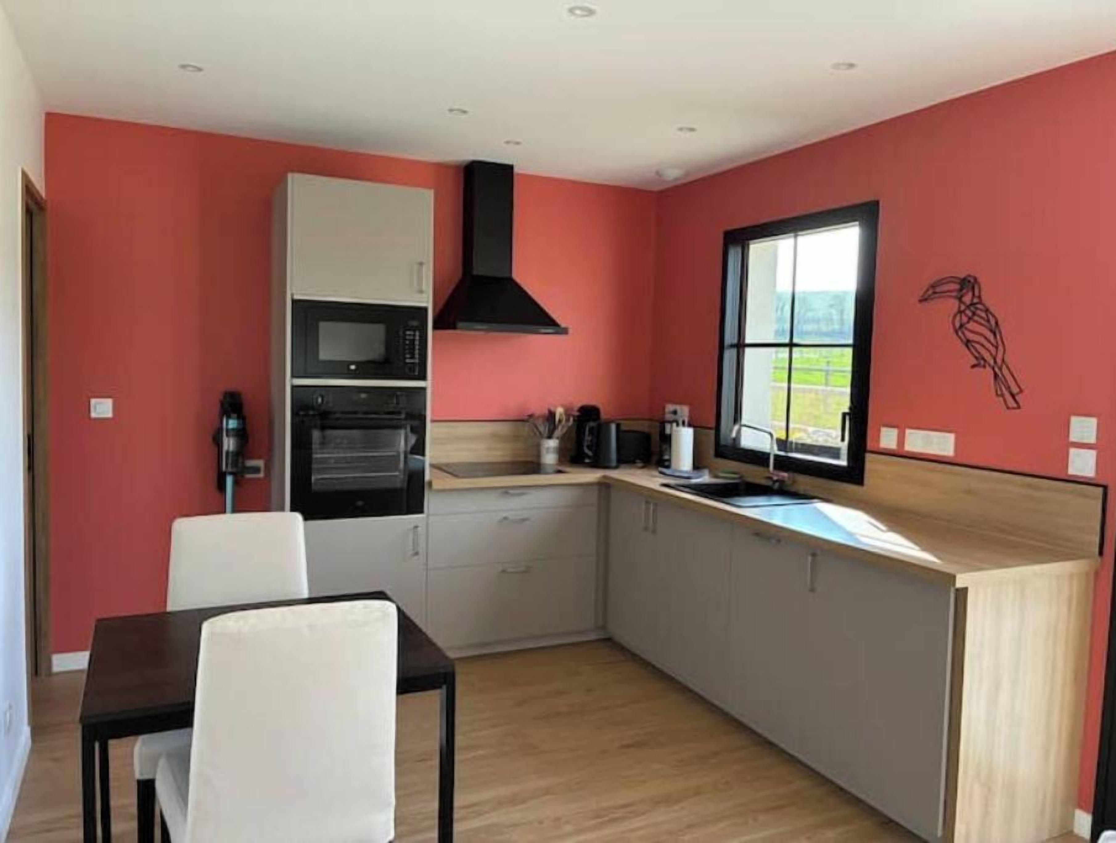 A compact kitchen with a microwave, oven, and sink, a dining area with a table and chairs, and a window with a view.