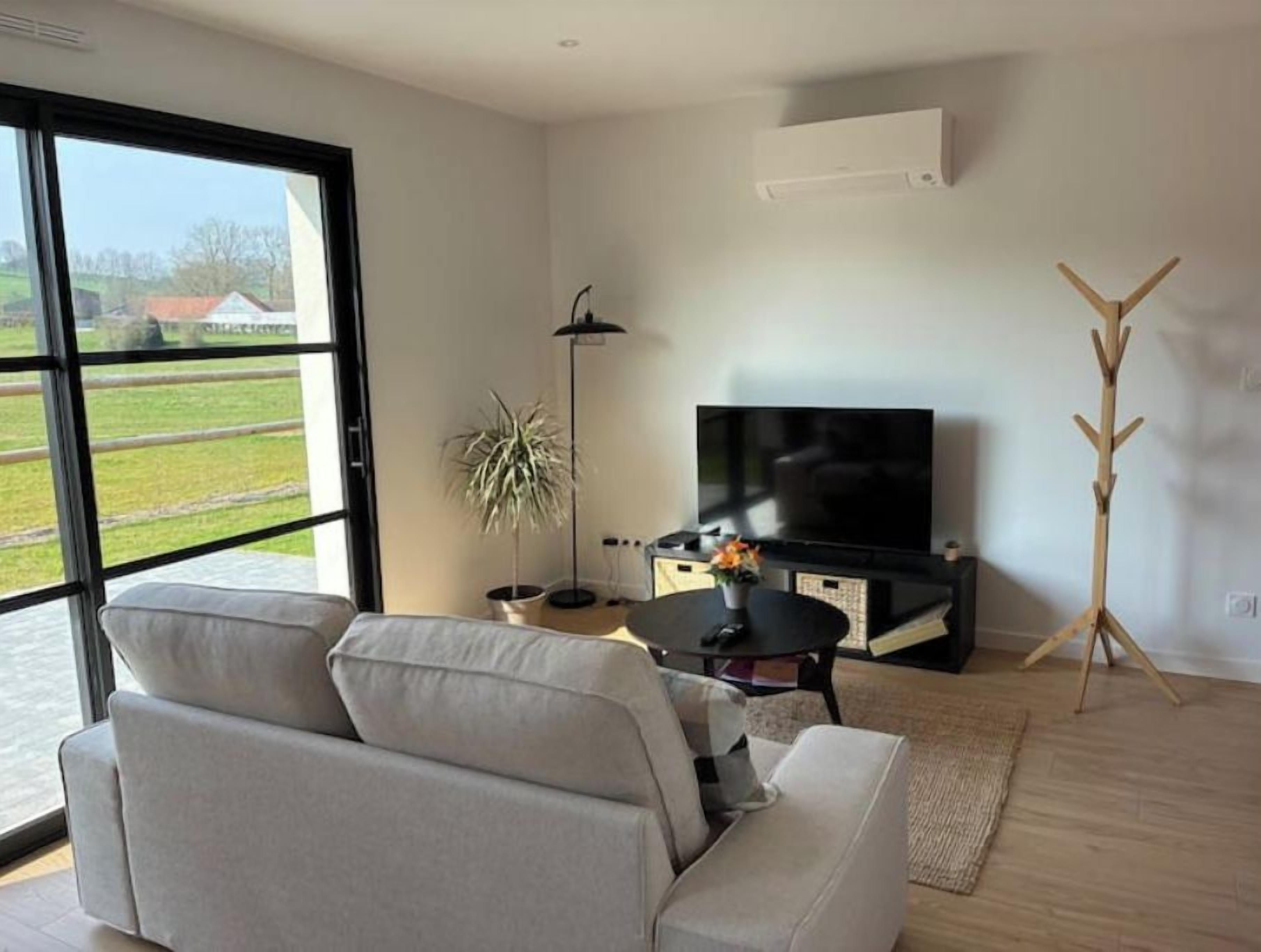 Una sala de estar moderna con un sofá, un televisor, una lámpara de pie y un atril.