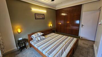 A bedroom with a bed, a ceiling fan, a wardrobe, and a door.