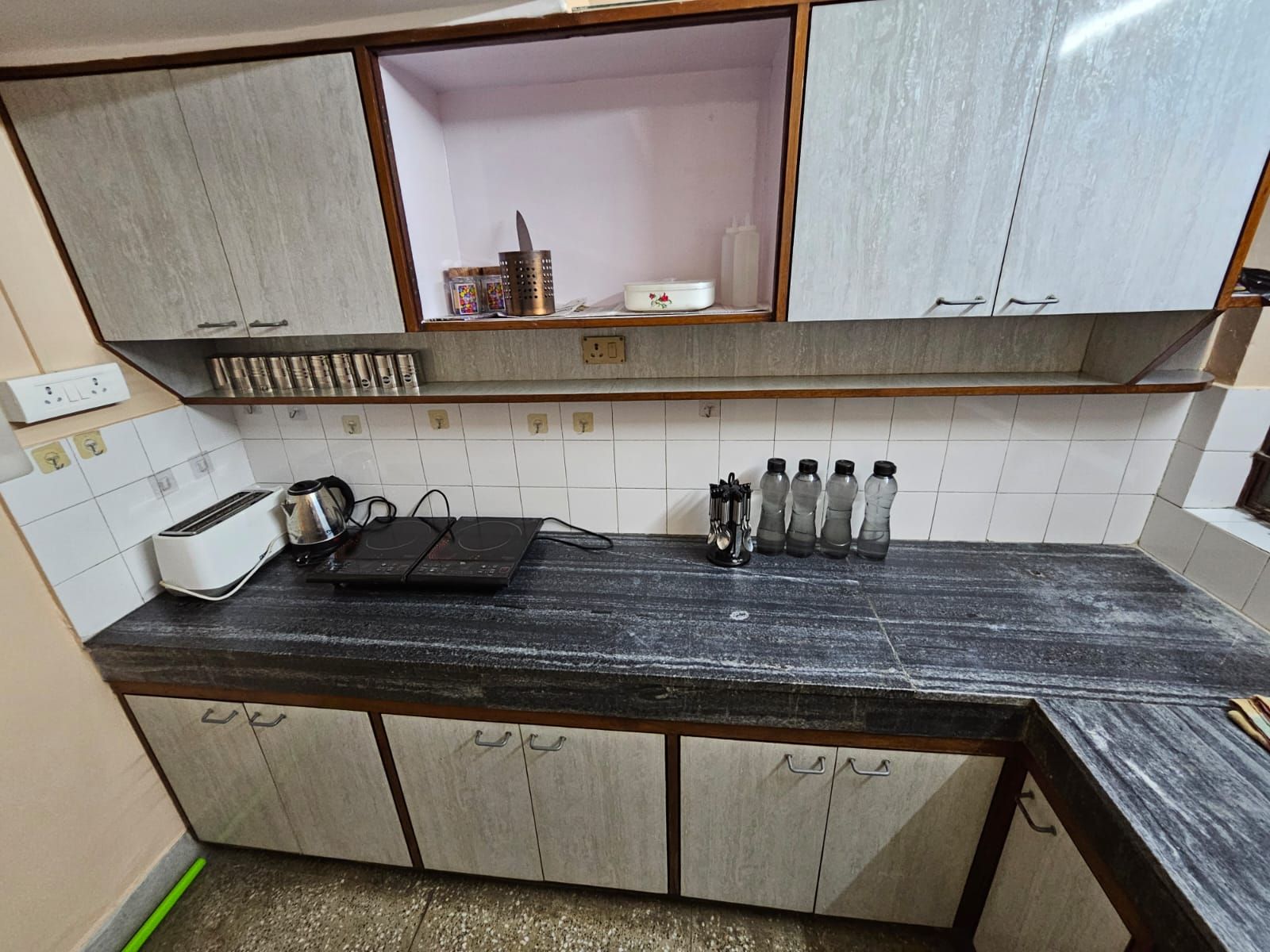 A kitchen with a black countertop, white tiled backsplash, and wooden cabinets.