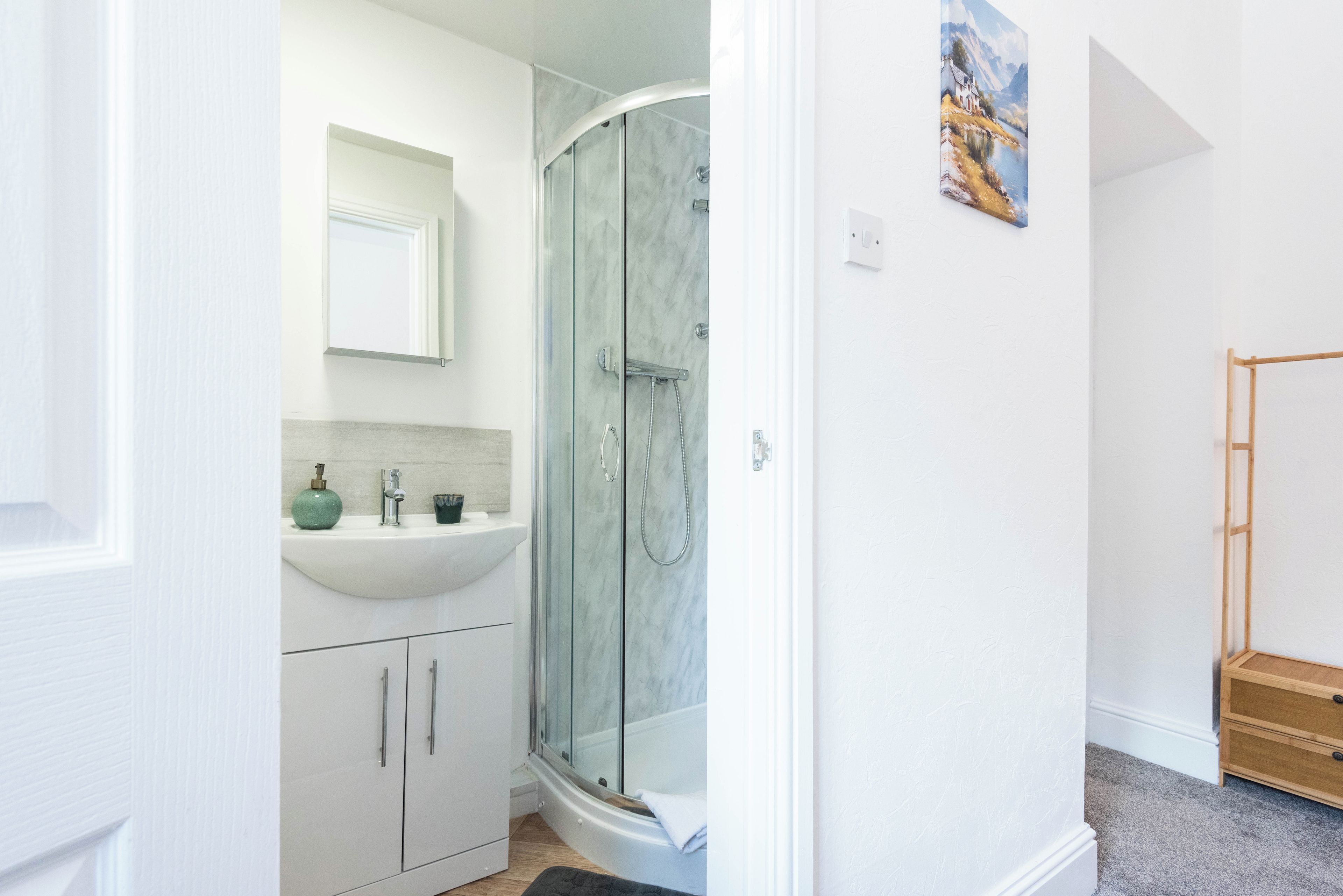 A bathroom with a glass-enclosed shower, a sink, and a mirror.