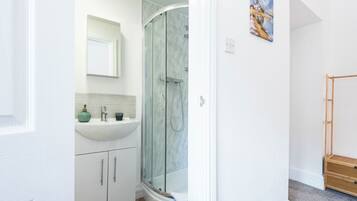 A bathroom with a glass-enclosed shower, a sink, and a mirror.