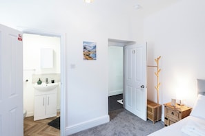 A hotel room with a bathroom, a bed, a bedside table, and a coat rack. - The Stanley Arms Hotel by Guestz (Seascale)