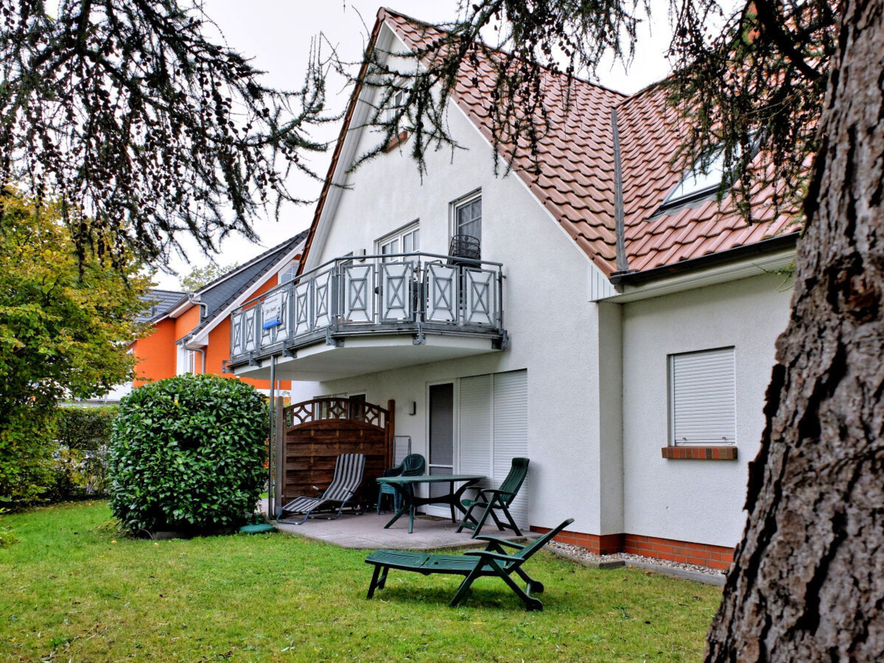 A residential building with a balcony, a patio with outdoor furniture, and a well-maintained lawn.