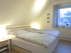 Ein Schlafzimmer mit einem Bett, einem Nachttisch und einem Fenster mit Vorhängen.