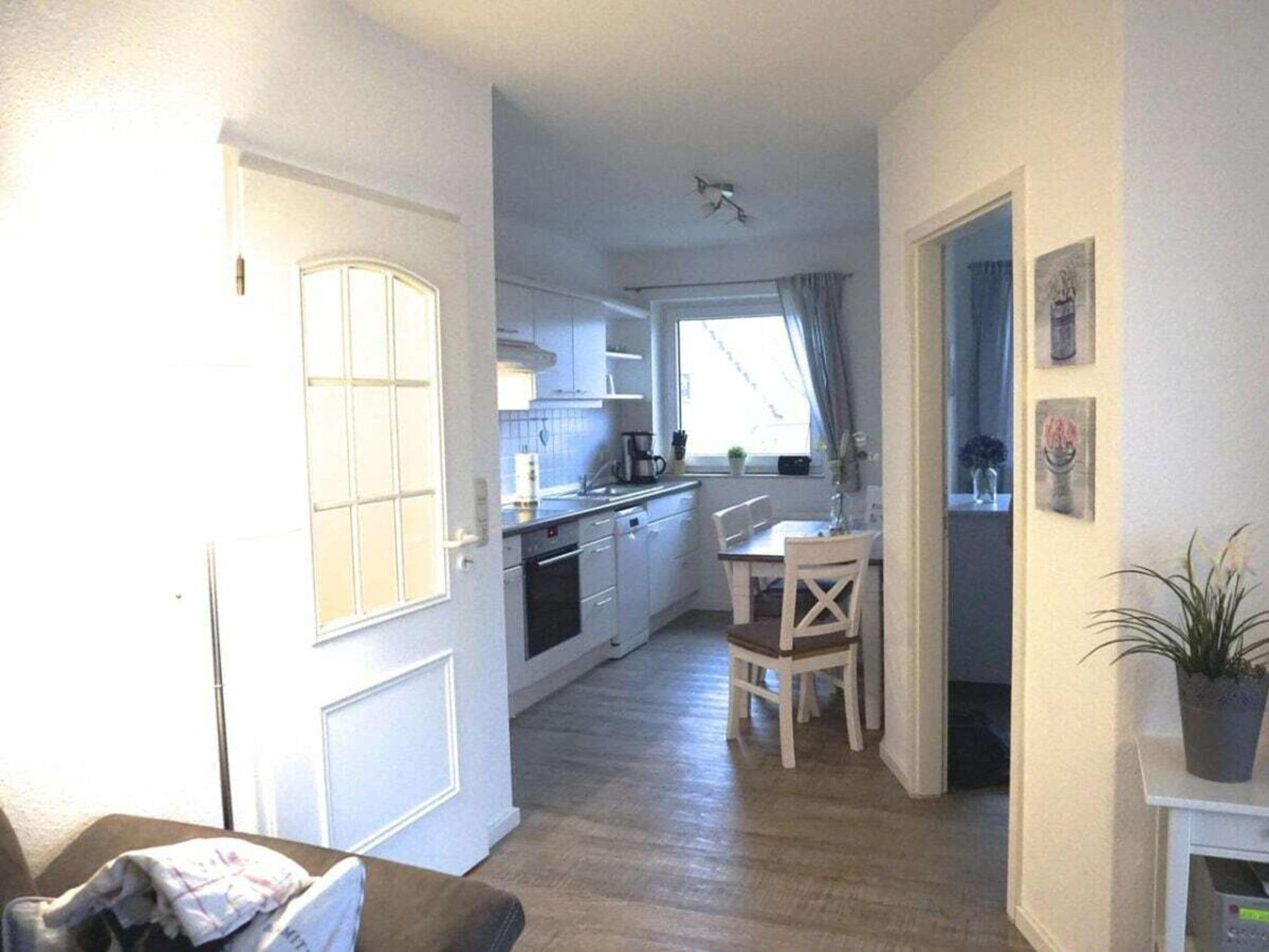 A compact kitchen with a dining area, a white door, and a small table with chairs.