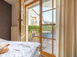 A room with a bed, a window, and a view of an outdoor patio area. - 2.1/t2 Holiday Home Park \"freesenbruch\" (Zingst)
