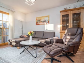 A modern living room with a sofa, a recliner, a coffee table, and a cabinet with glass doors. - 2.1/t2 Holiday Home Park \"freesenbruch\" (Zingst)