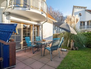A patio area with a table and chairs, a blue chair, a white wall, and a window. - 2.1/t2 Holiday Home Park \"freesenbruch\" (Zingst)