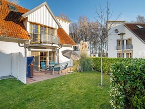 A two-story house with a balcony, a patio with outdoor furniture, and a well-maintained lawn. - 2.1/t2 Holiday Home Park \"freesenbruch\" (Zingst)