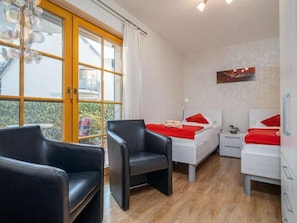 Een hotelkamer met een bed, twee nachtkastjes, een stoel en een raam met gordijnen.