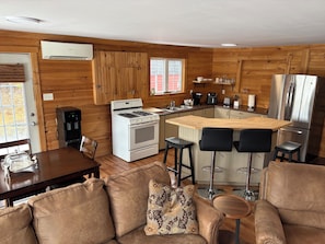 A compact kitchen with a stove, refrigerator, and bar stools.