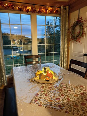 A dining table with a floral tablecloth, a candle, and a decorative centerpiece.