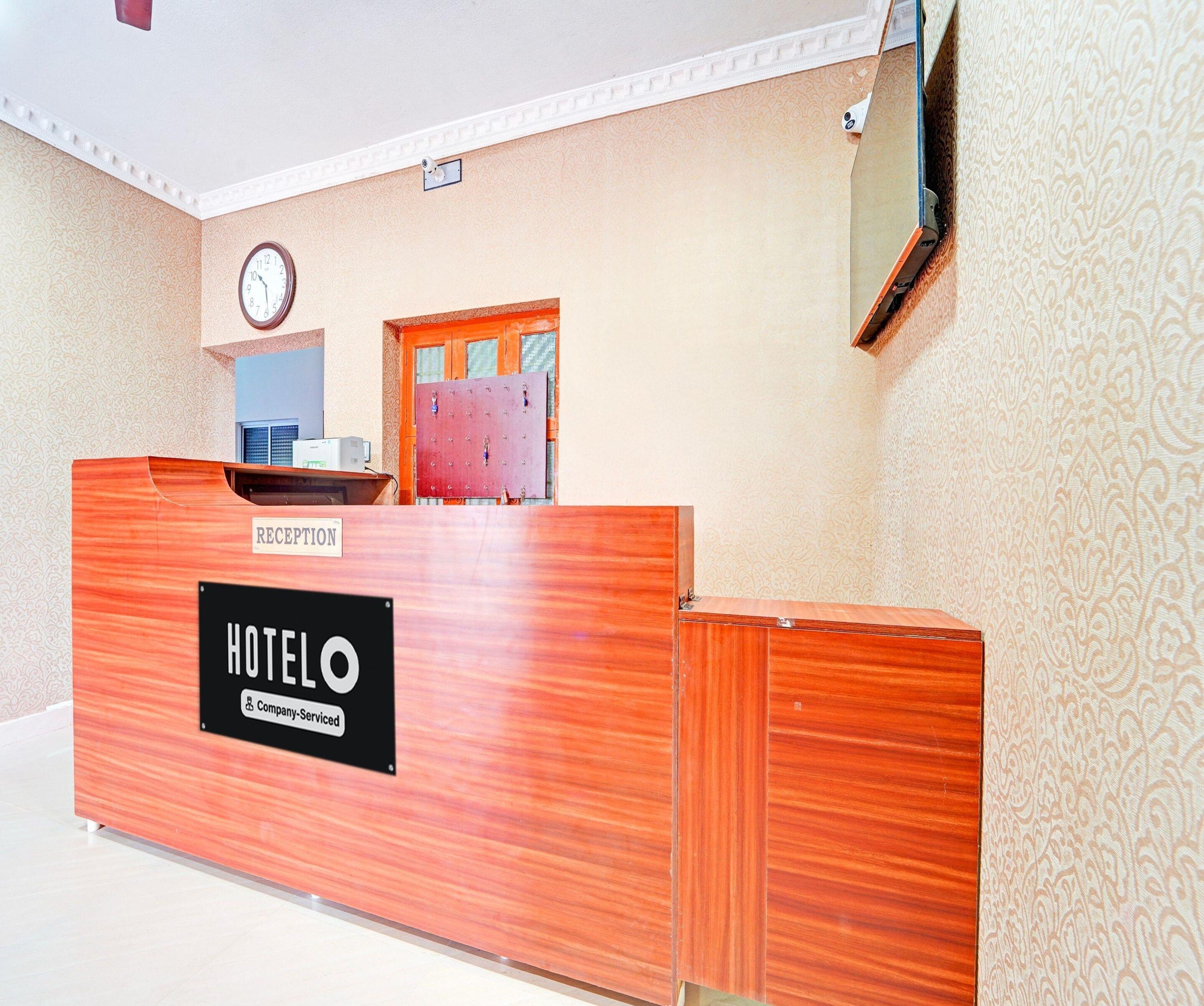 A reception desk labeled 'HOTEL' with a clock above it, a patterned wall, and a door with a window.