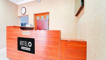 A reception desk labeled 'HOTEL' with a clock above it, a patterned wall, and a door with a window.