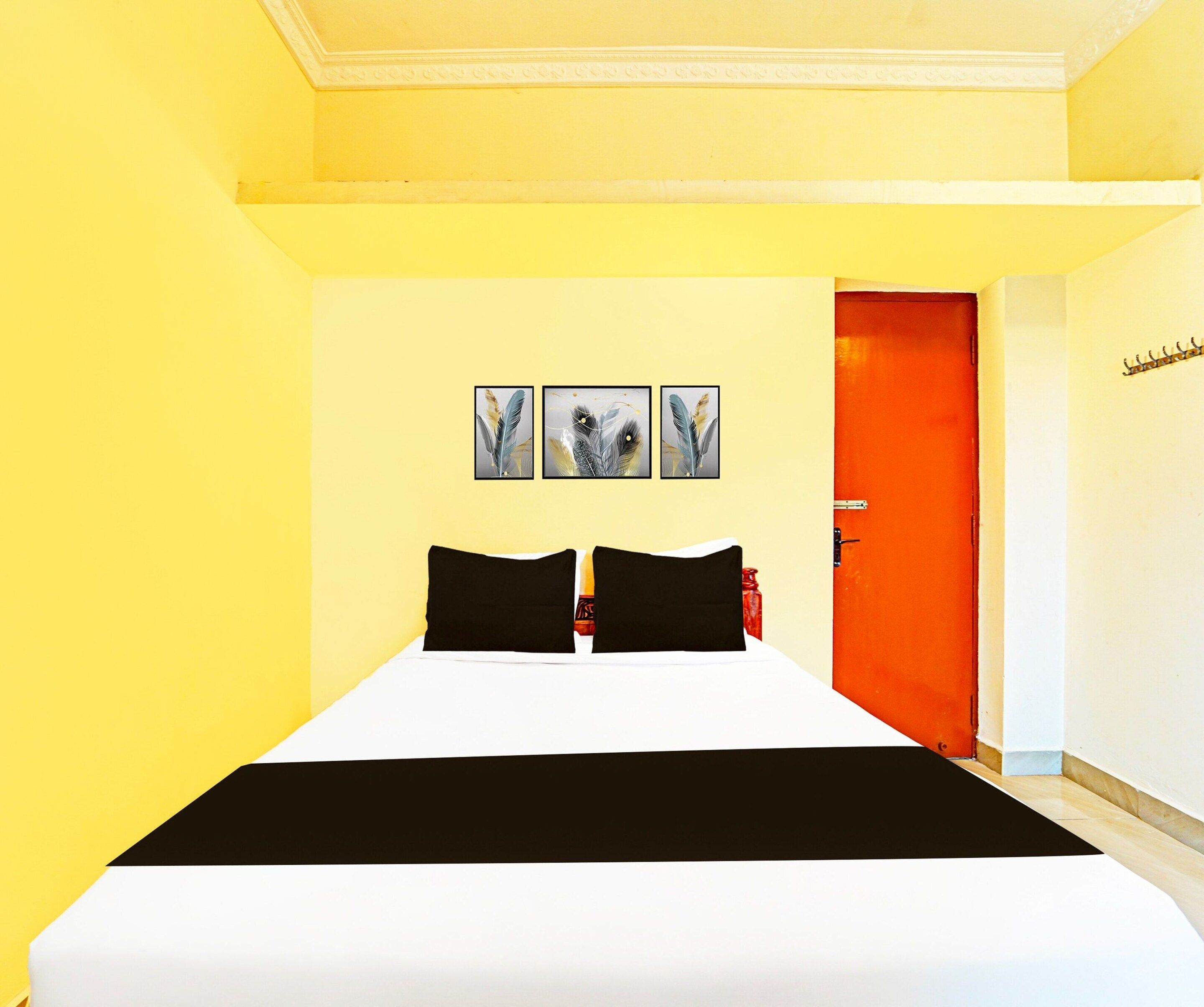 Une chambre d’hôtel avec un lit, une porte et trois tableaux accrochés au mur.