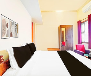 A hotel room with a bed, a desk, a chair, and a wardrobe. - Deluxe KS Comfort (Chidambaram)