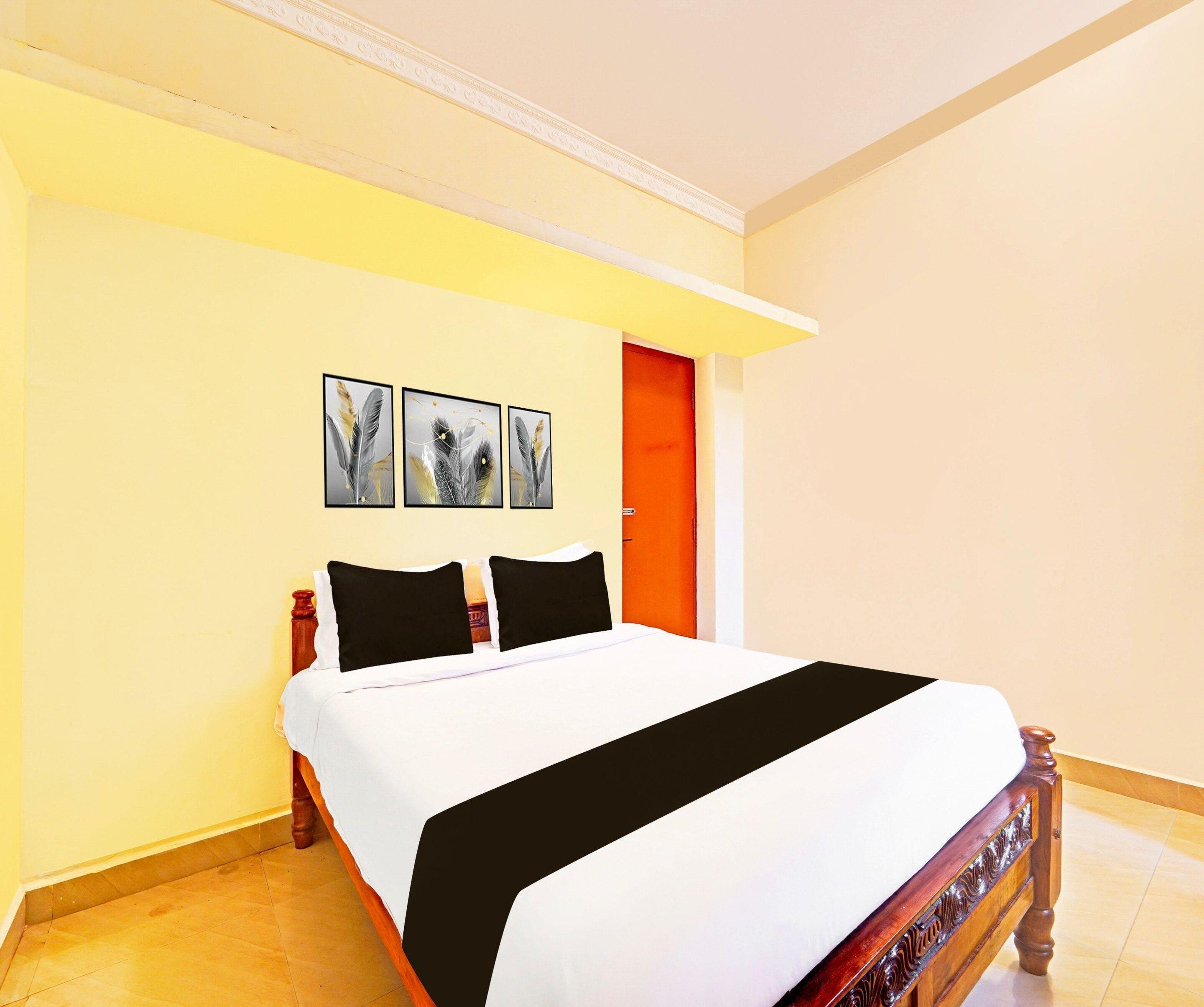 Une chambre d’hôtel avec un lit, une porte et deux tableaux encadrés au mur.