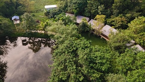A resort with multiple bungalow-style buildings surrounded by dense greenery and a body of water.
