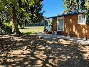 A wooden cabin with a covered porch, a window, and a door.