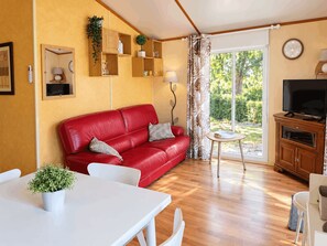 A cozy living room with a red sofa, a dining table, and a TV.