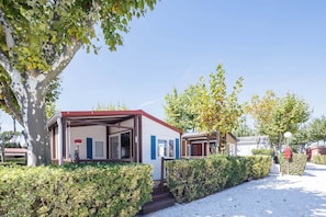 Una hilera de pequeñas construcciones de una sola planta con porches abiertos, rodeadas de setos y árboles bien cuidados.