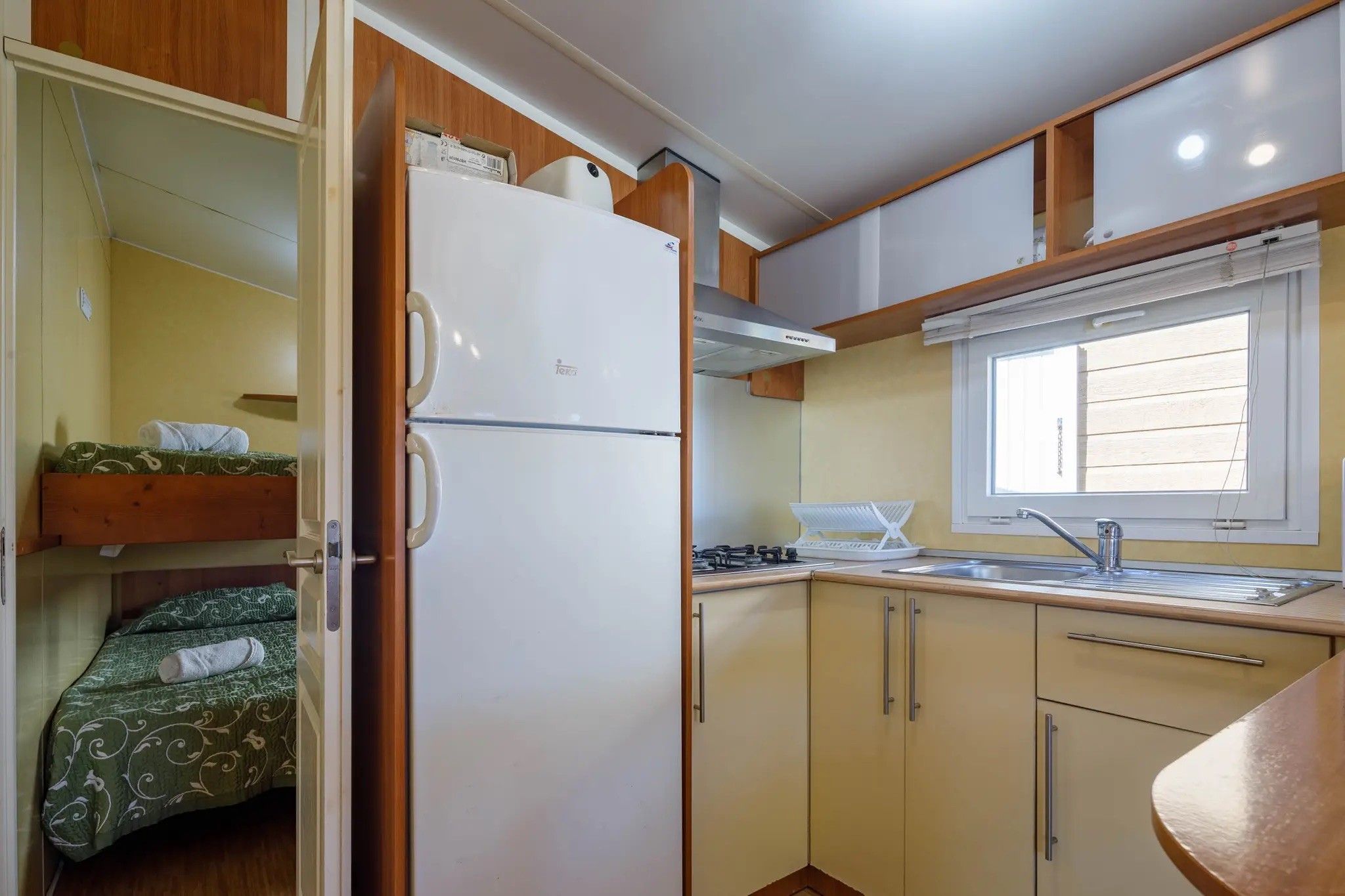 Una cocina compacta con refrigerador, lavamanos y ventana.