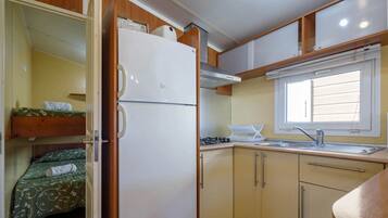 Una cocina compacta con refrigerador, lavamanos y ventana.