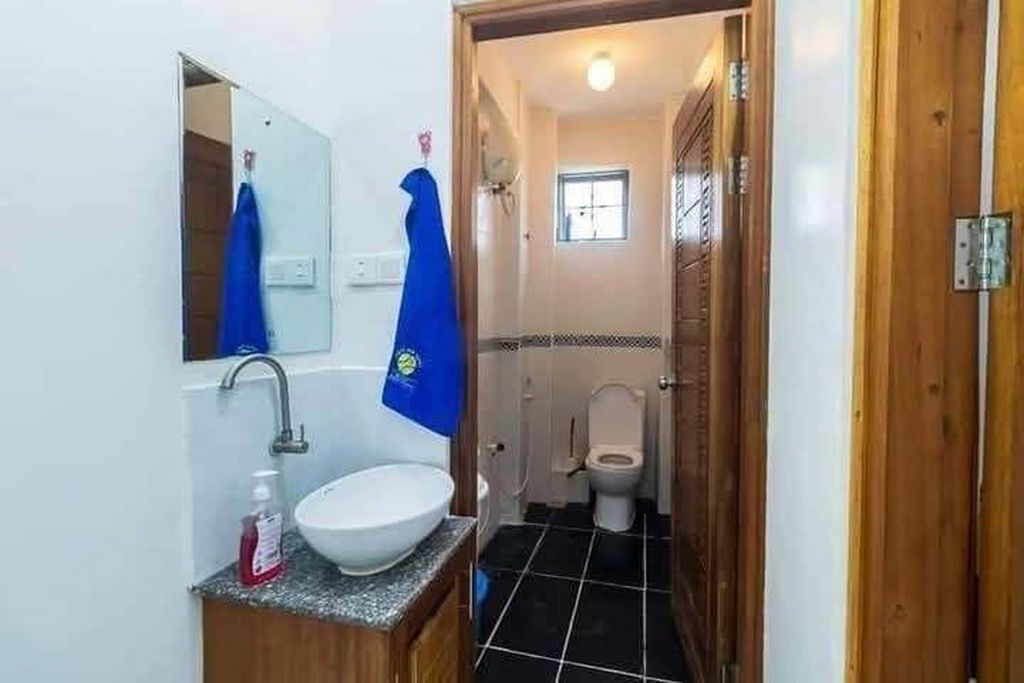 Een badkamer met een witte wasbak, een spiegel, een blauwe handdoek en een toilet.