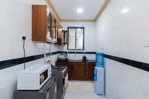 A compact kitchen with a microwave, stove, and cabinets. - Serene 1-bedroom apartment in the heart of Mombasa (Mombasa)