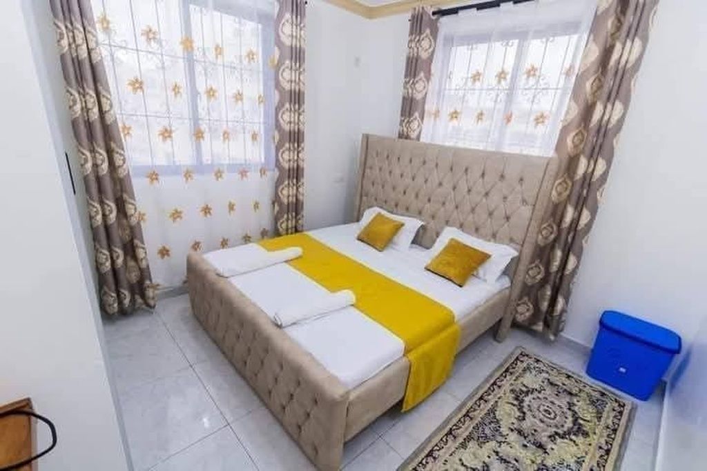 Un dormitorio con cama, cortinas y alfombra.