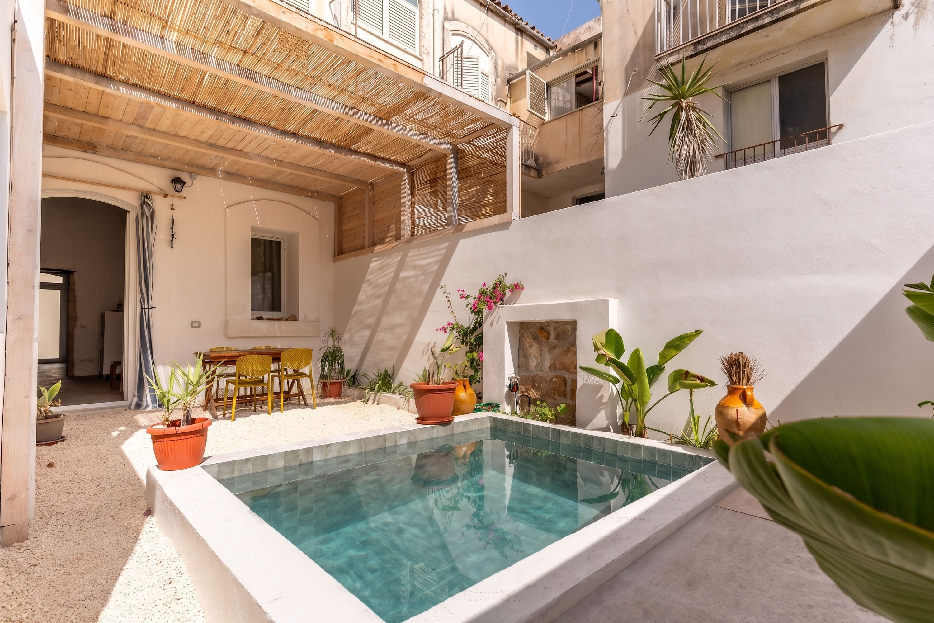 Un espace piscine agrémenté d’une pergola en bois, de sièges d’extérieur et de plantes en pot.