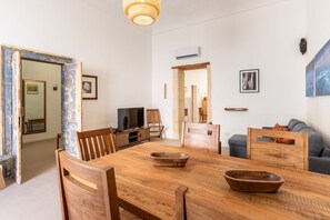 A dining area with a wooden table, chairs, and a television. - Approdo Mediterraneo by Wonderful Italy (Syracuse)