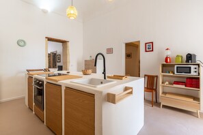 A compact kitchen with a central island, a microwave, and a sink. - Approdo Mediterraneo by Wonderful Italy (Syracuse)