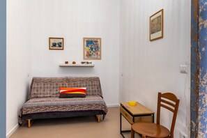 A small, cozy room with a patterned sofa, a wooden chair, a small table, and two framed pictures on the wall. - Approdo Mediterraneo by Wonderful Italy (Syracuse)