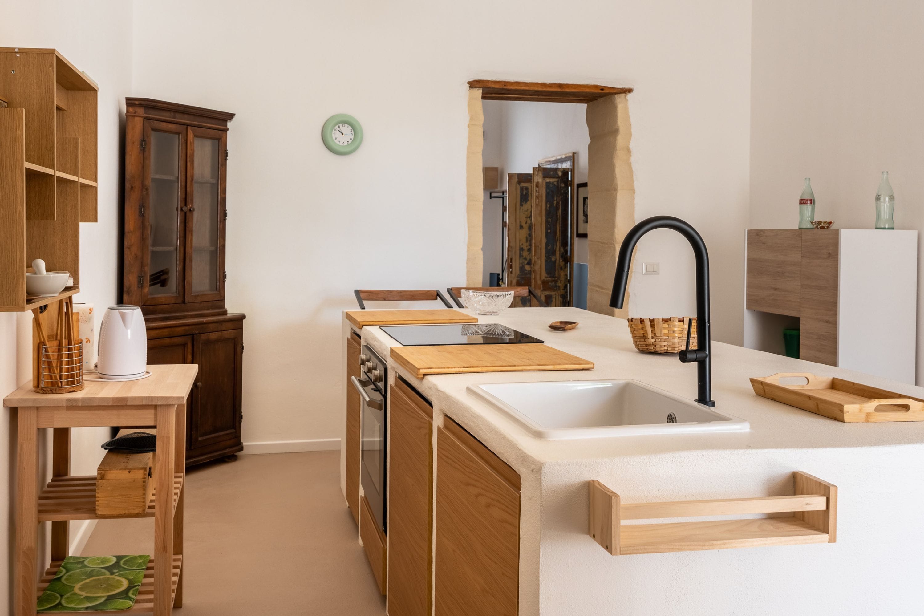 A modern kitchen with wooden cabinetry, a central island with a sink, and a built-in oven.