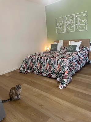 A bedroom with a floral bedspread, a cat on the floor, and wall art. - Bed& Breakfast  Florida 7 - camera 2 (Pertegada)