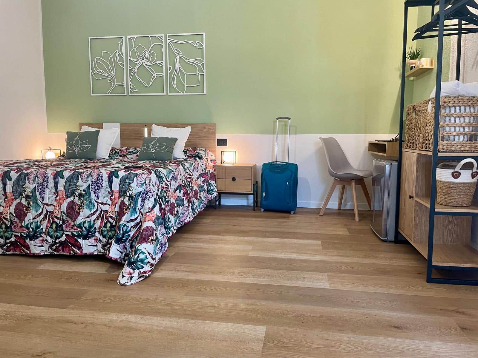 Une chambre d’hôtel équipée d’un lit, d’un bureau, d’une chaise, d’une armoire et d’œuvres d’art accrochées au mur.