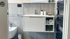 Een moderne badkamer met een ingebouwd wastafelmeubel, een spiegel en een plank met handdoeken.