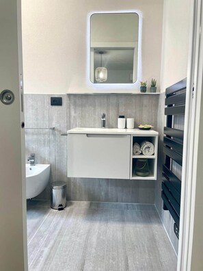 A modern bathroom with a built-in sink, a mirror, and a shelf with towels. - Bed& Breakfast  Florida 7 - camera 2 (Pertegada)