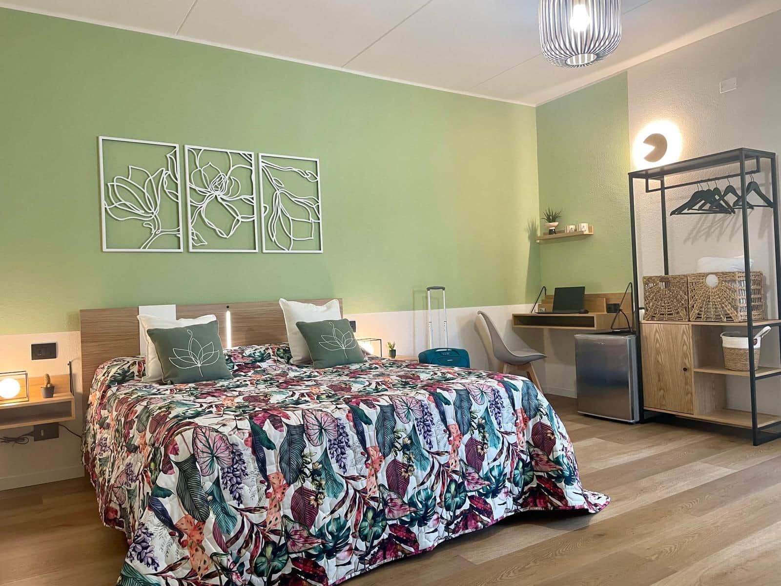 Une chambre d’hôtel avec un lit, un bureau, une chaise, une armoire et des œuvres d’art accrochées au mur.