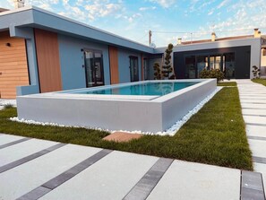 Una casa moderna con piscina, un camino empedrado y un césped cuidado.