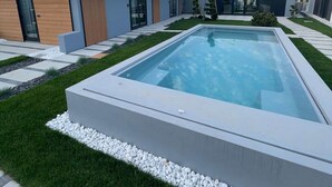 Een modern huis met een zwembad, een verzorgd gazon en een heldere lucht.