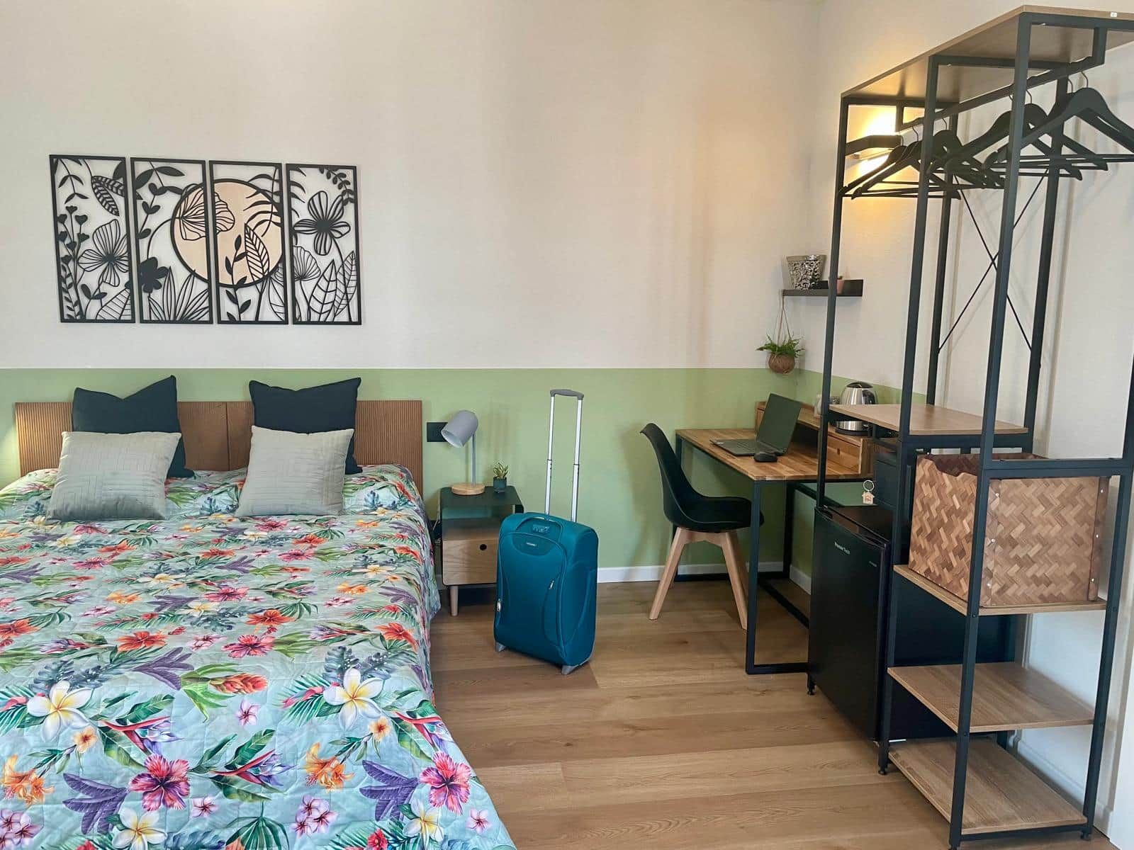 Une chambre d’hôtel comprenant un lit, un bureau, une chaise, une armoire et une œuvre d’art murale.