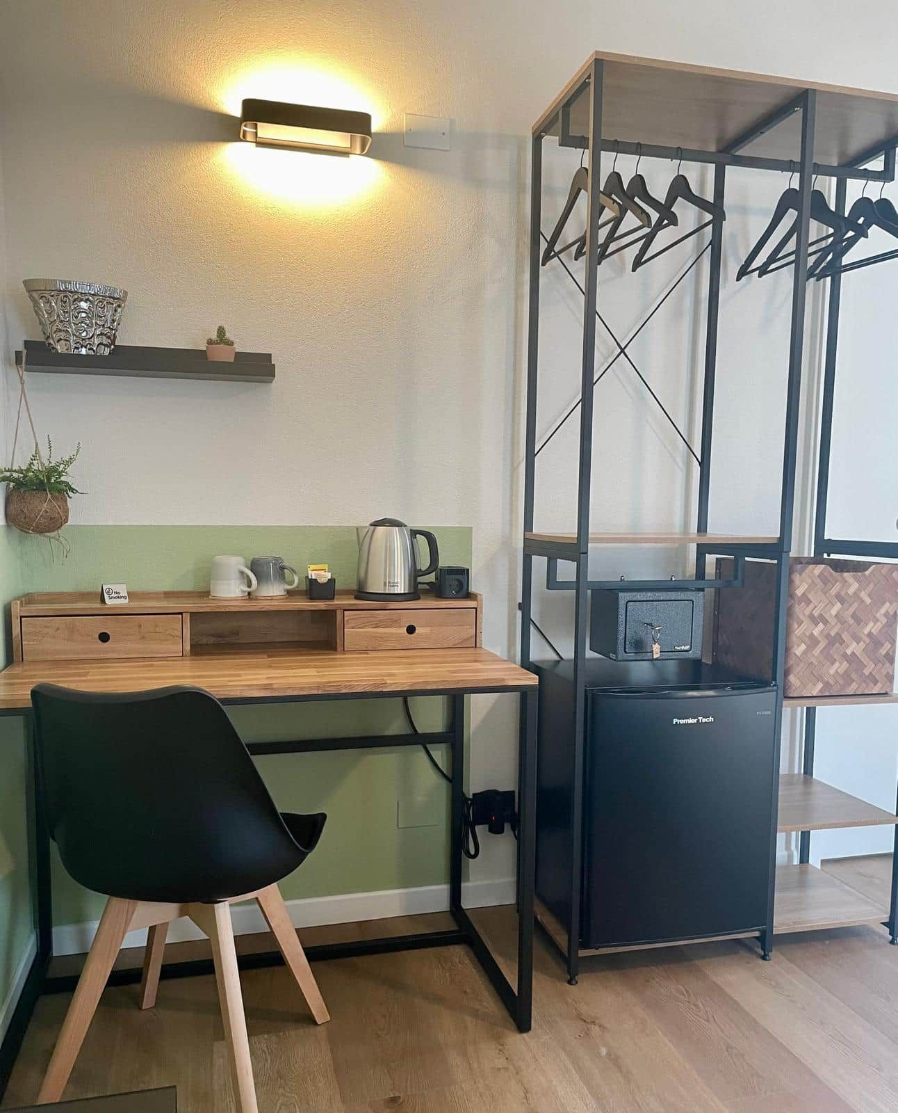 Ein kleines Zimmer mit Schreibtisch, Stuhl und kleinem Kühlschrank.