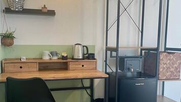 Ein kleines Zimmer mit Schreibtisch, Stuhl und kleinem Kühlschrank.
