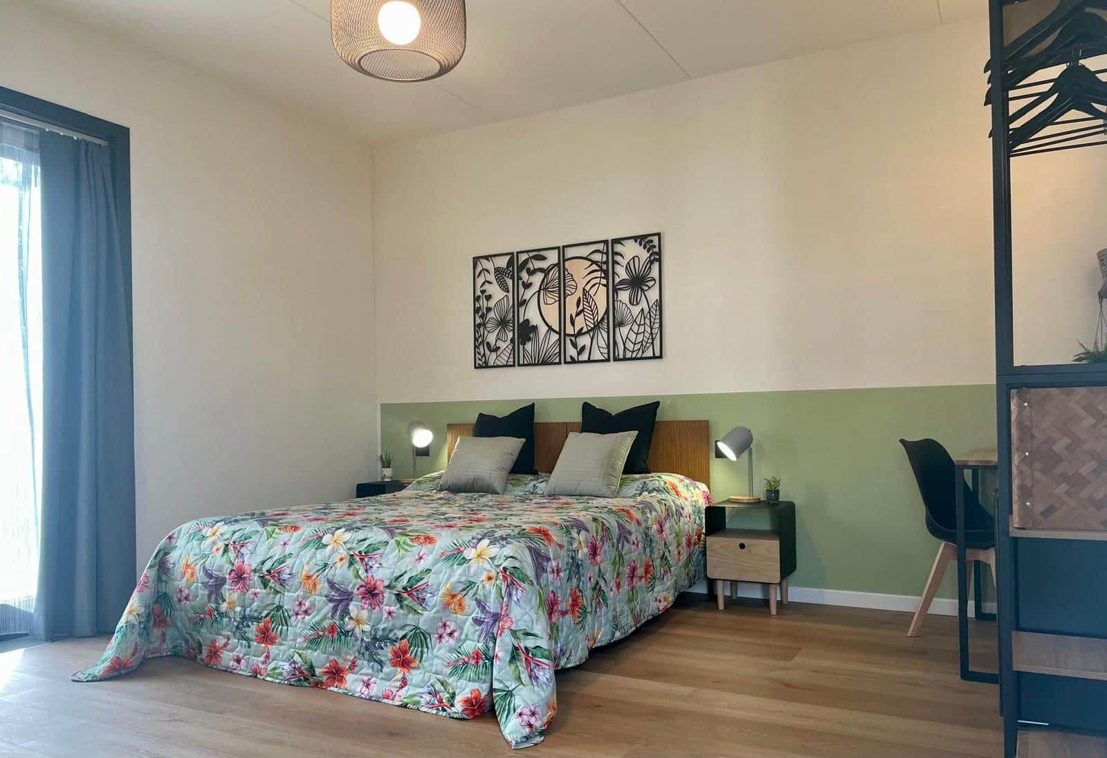 Une chambre à coucher comprenant un lit, des tables de chevet, une œuvre d’art murale et une chaise.
