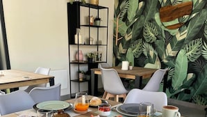 Een ontbijtsetting met diverse etenswaren, zoals gebak, fruit en dranken, op een houten tafel gerangschikt.