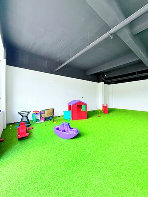 A room with artificial grass flooring, a playhouse, a small boat, and a chair. - Stylish Kilimani 2BR with Pool, Wi-Fi and Free Parking near Yaya Centre (Nairobi)